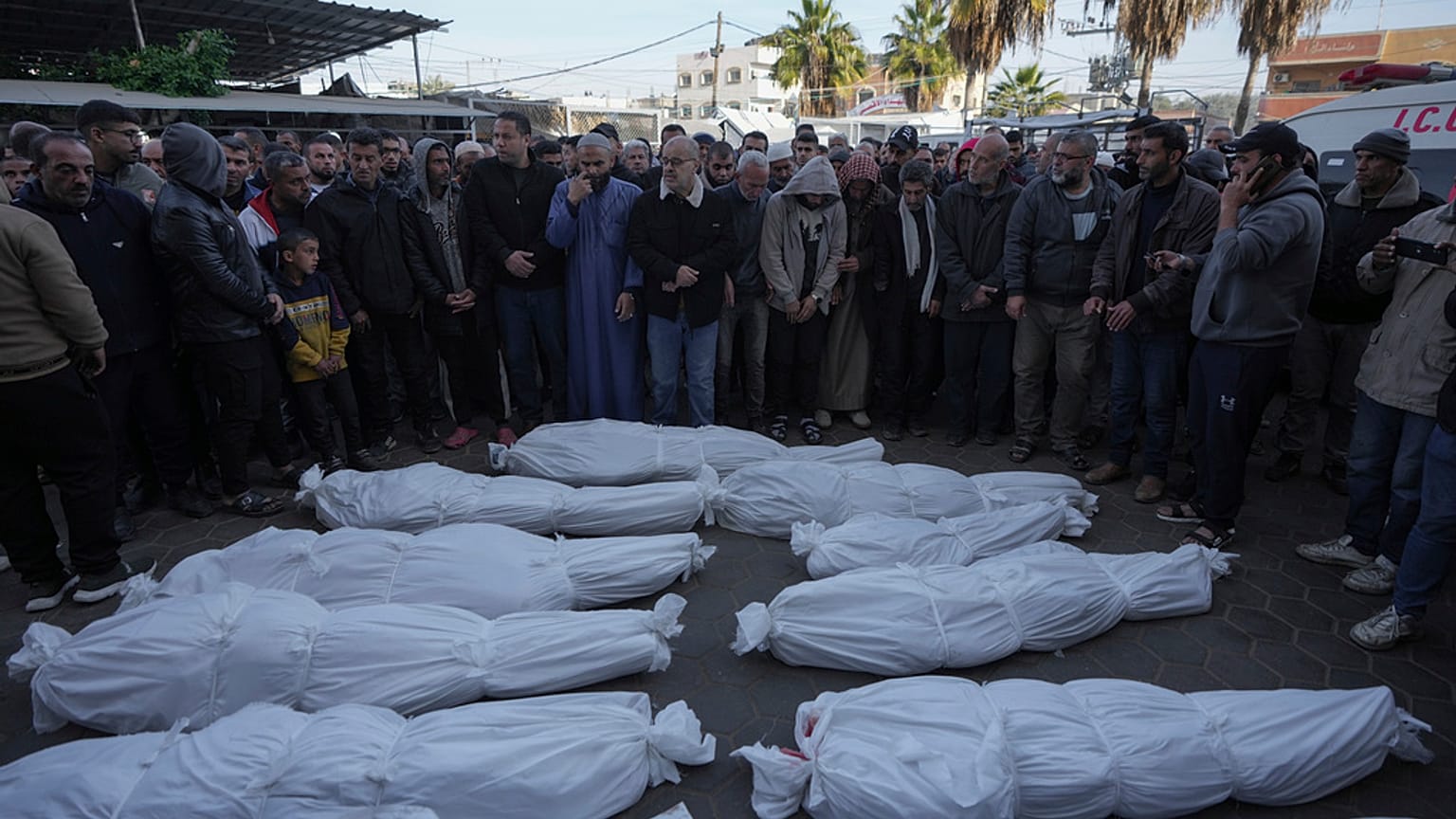Pessoas enlutadas rezam junto aos corpos dos palestinianos mortos nos bombardeamentos israelitas na Faixa de Gaza no Hospital Al-Aqsa em Deir al-Balah.