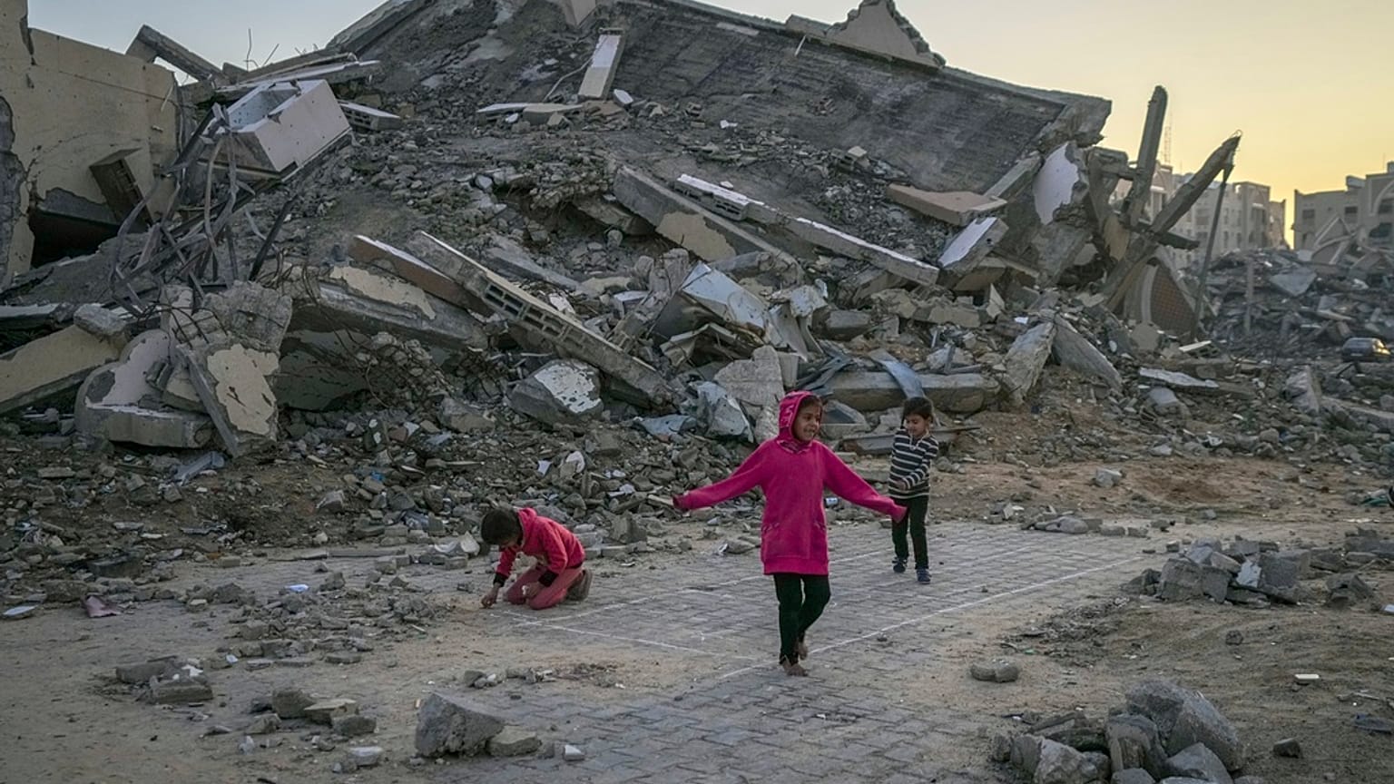 أطفال فلسطينيون يلعبون بجانب مبنى دمره الجيش الإسرائيلي في بلدة خان يونس وسط قطاع غزة، في 1 يناير 2025. 