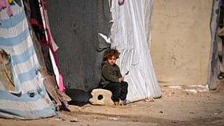 طفل يجلس أمام خيمة بمخيم للنازحين الفلسطينيين في دير البلح، وسط قطاع غزة، الجمعة 17 يناير 2025.