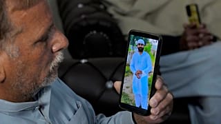 Mohammad Akram mostra una foto del figlio Abu Bakar, che si teme sia annegato, sul suo cellulare nel villaggio di Jura, in Pakistan, 17 gennaio 2024