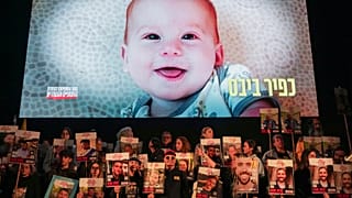Manifestantes seguram retratos de reféns detidos pelo Hamas na Faixa de Gaza enquanto é exibido um vídeo com Kfir Bibas, que, juntamente com os seus pais Shiri e Yarden Bibas,