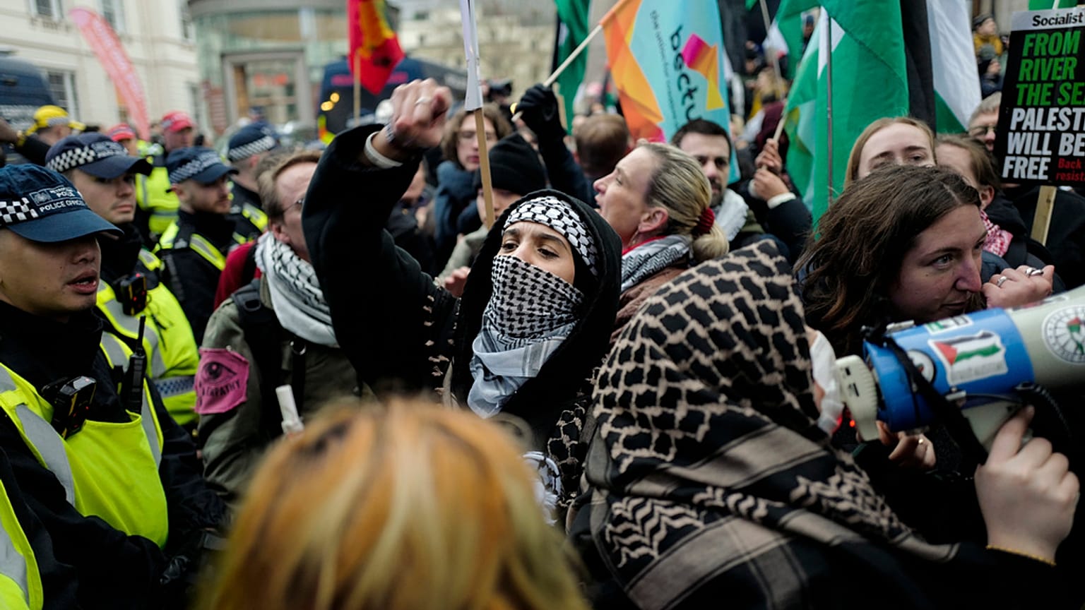 People hold flags and placards as they are are contained by police officers, during a rally in support of the Palestinian People in Gaza, in London, Saturday, Jan. 18, 2025.