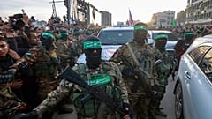 مقاتلو حماس يرافقون سيارة تابعة للصليب الأحمر لتسلم الأسرى الإسرائيليين الذين تم الإفراج عنهم بعد دخول اتفاق وقف إطلاق النار بين إسرائيل وحماس حيز التنفيذ، في مدينة غزة، 2025
