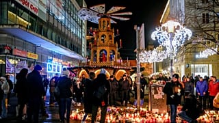 Pessoas assistem a uma campanha eleitoral da AfD perto do Mercado de Natal em Magdeburgo, Alemanha, segunda-feira, 23 de dezembro de 2024.