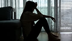 Eine Frau sitzt mit dem Kopf in ihren Händen.