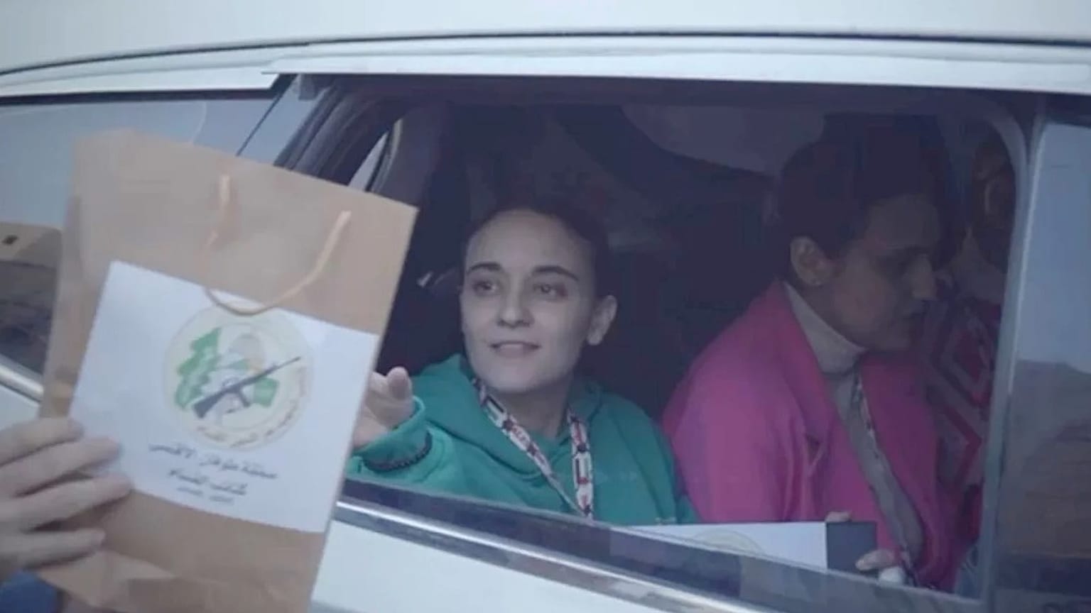 Rehineler, Kızılhaç'a ait bir SUV ile Gazze'den ayrılırken bir militanın bir rehineye hediyelik çanta uzattığı görülüyor, 19 Ocak Pazar
