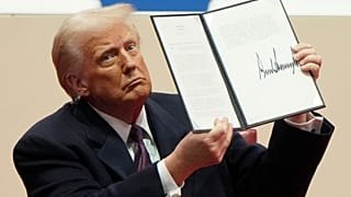 O presidente Donald Trump segura uma ordem executiva depois de a assinar durante um evento interno durante a cerimónia de tomada de posse presidencial em Washington.