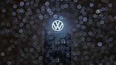 Yağmur damlaları bir otomobilin ön camında toplanırken Volkswagen marka kulenin çatısındaki logo arkada parlıyor. Wolfsburg, Almanya. 9 Aralık 2024.