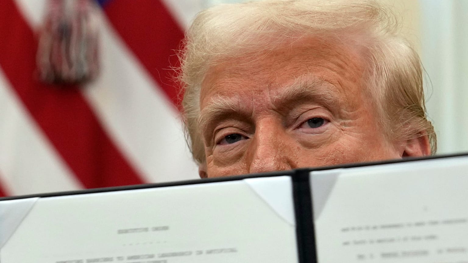Donald Trump muestra una orden ejecutiva tras firmarla. 