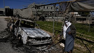  Bir Filistinli, Batı Şeria'daki bir köyde İsrailli yerleşimciler tarafından düzenlendiğinden şüphelenilen saldırının ardından yakılan bir arabanın yanında duruyor