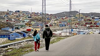 Grönland'ın batısındaki Aasiaat Takımadaları'nın kalbindeki aynı isimli adada bulunan Aasiaat kasabasında iki kişi yürüyor, 29 Haziran 2024.