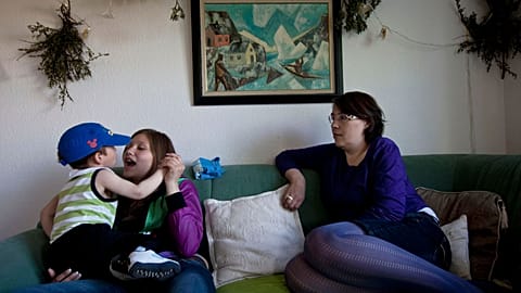 In this July 21, 2011 photo, Inuit family members Natuk C. Molgaard, 13, holds her 22-month-old nephew, Inutsiaq as they sit next to their mother and grandmother.