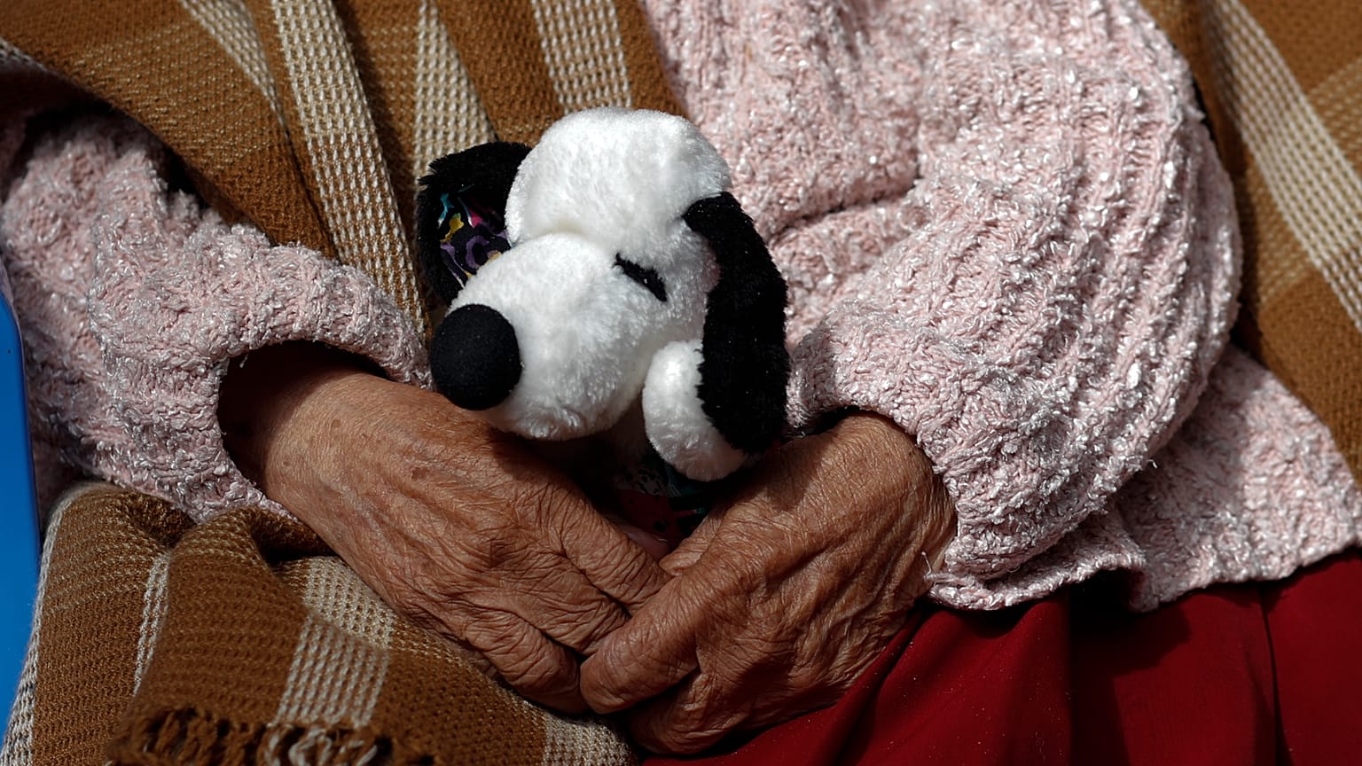 Egy nő tartja a kitömött Snoopy kutyáját egy bolíviai idősek otthonában 2021 áprilisában.