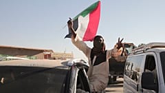 سوداني يلوح بعلم بلاده عقب تقارير عن دخول الجيش السوداني إلى مدينة ود مدني وسط البلاد، كانون الثاني/يناير 2025.