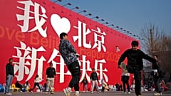 Chinesen spielen in der Nähe einer riesigen Anzeigetafel mit der Aufschrift "I Love Beijing, Happy New Year 2025" in Peking Verschlußhahn