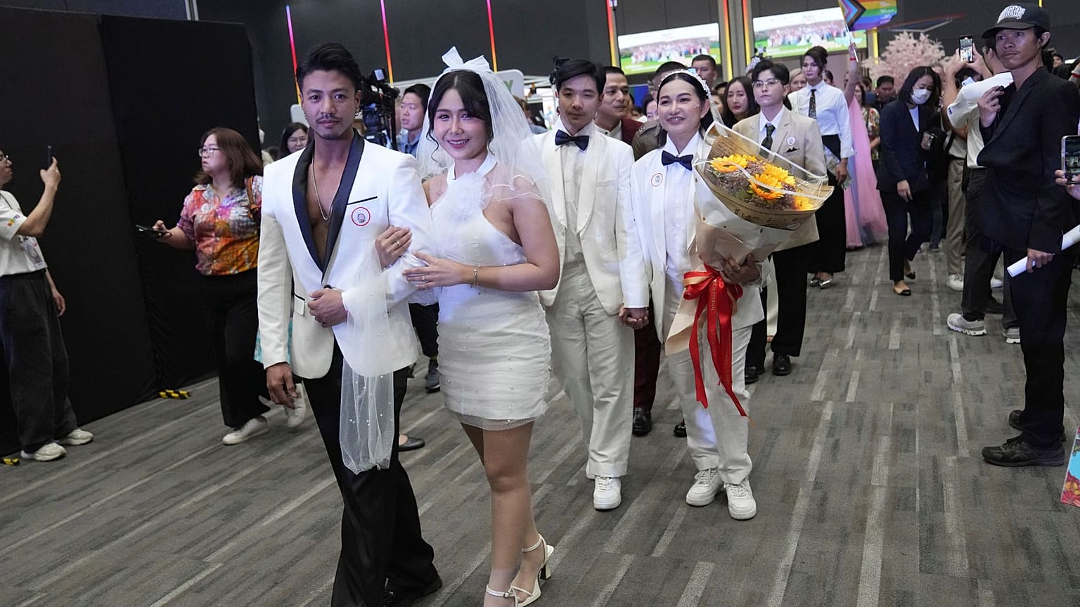 Parejas de la comunidad LGBTQ+ desfilan hacia una sala tras la entrada en vigor de la Ley de matrimonio igualitario en Bangkok, Tailandia, el jueves 23 de enero de 2025.