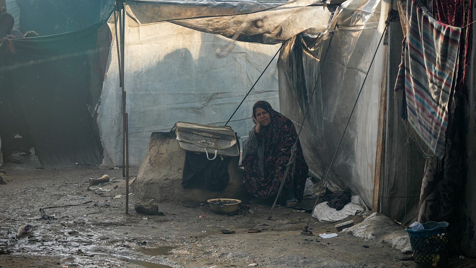 سميرة ضيف الله، 52 عامًا، نازحة من مدينة غزة، تجلس خارج خيمتها بعد ليلة من هطول الأمطار الغزيرة في دير البلح وسط قطاع غزة، الخميس 23 يناير/كانون الثاني 2025