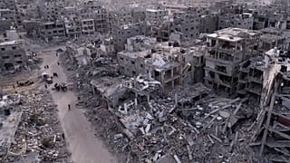  فلسطينيين يسيرون وسط الدمار الذي خلفه الهجوم الجوي والبري الإسرائيلي في رفح، قطاع غزة، الثلاثاء، 21 يناير/كانون الثاني 2025