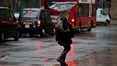 Der Regenschirm einer Frau wird von innen nach außen geweht, als sie durch einen heftigen Regenschauer im Londoner Geschäftsviertel Canary Wharf geht, Mittwoch, 20. November 2013.
