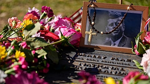 FILE - A rosary covers a photograph of President John F. Kennedy at a marker along Elm Street, Dallas, Nov. 22, 2023