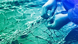 DOSSIER : Un membre de l'équipage du navire de pêche Sophie Louise II répare les filets déchirés sur le quai, à North Shields, dans le nord-est de l'Angleterre, en décembre 2007.