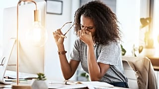 امرأة تفرك عينيها بعد العمل على الكمبيوتر.