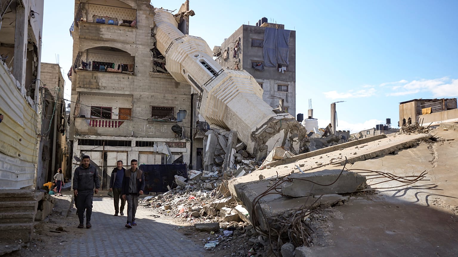 Palestinos pasan frente a una mezquita destruida por los ataques aéreos israelíes en Nuseirat, Franja de Gaza, el viernes 24 de enero de 2025