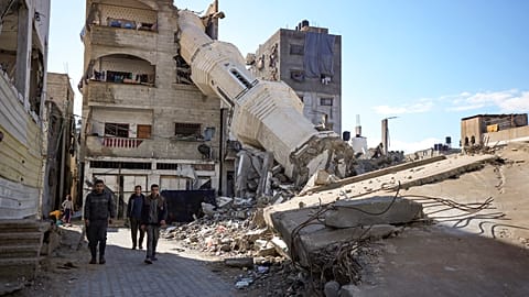 Palestinos pasan frente a una mezquita destruida por los ataques aéreos israelíes en Nuseirat, Franja de Gaza, el viernes 24 de enero de 2025