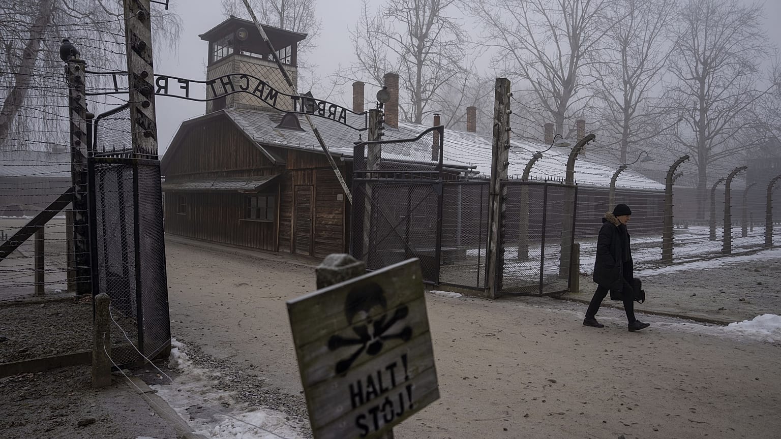 Un homme passe devant la porte "Arbeit Macht Frei" (Le travail rend libre) au Mémorial et Musée d'Auschwitz-Birkenau, 23 janvier 2025.