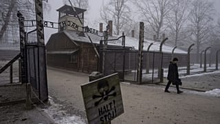Un homme passe devant la porte "Arbeit Macht Frei" (Le travail rend libre) au Mémorial et Musée d'Auschwitz-Birkenau, 23 janvier 2025.