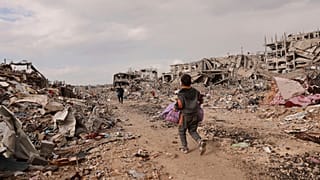 فتى فلسطيني يحمل أغراضه الشخصية بينما يمشي مع عائلته بجانب أنقاض منازل مدمرة، عقب اتفاق وقف إطلاق النار، في مدينة غزة، يوم الجمعة، 24 يناير 2025.