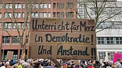 İnsanlar 25 Ocak 2025 Cumartesi günü Almanya'nın Köln kentinde aşırı sağı protesto etmek için toplandı. Pankartta şunlar yazıyor: "Merz için demokrasi ve dürüstlük konusunda acil dersler". (Christoph Dr.