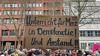 People gather to protest against the Far Right, in Cologne, Germany, Saturday Jan. 25, 2025. Banner reads: "Immediate lessons for Merz in democracy and decency". (Christoph Dr