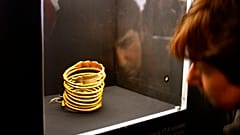 DATEI - Eine Frau betrachtet ein antikes dakisches Goldarmband, das im Nationalen Geschichtsmuseum in Bukarest, Rumänien, ausgestellt ist, Montag, 22. Januar 2007