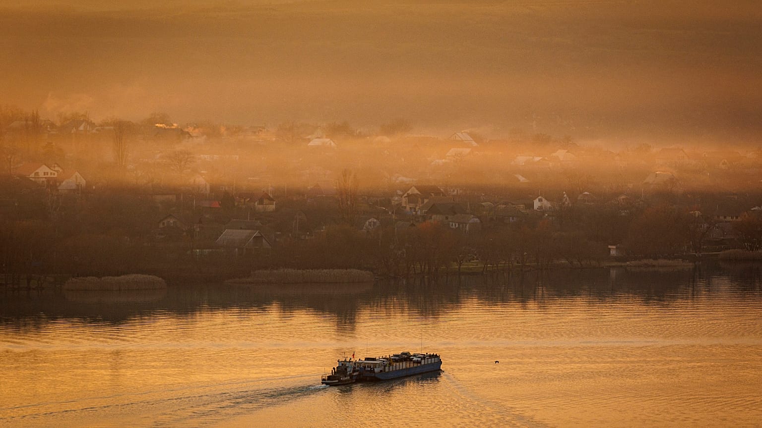 Um ferry navega para a margem esquerda do rio Dniester, a fronteira entre a Moldávia e a Transnístria, visto da Moldávia, 8 de janeiro de 2025