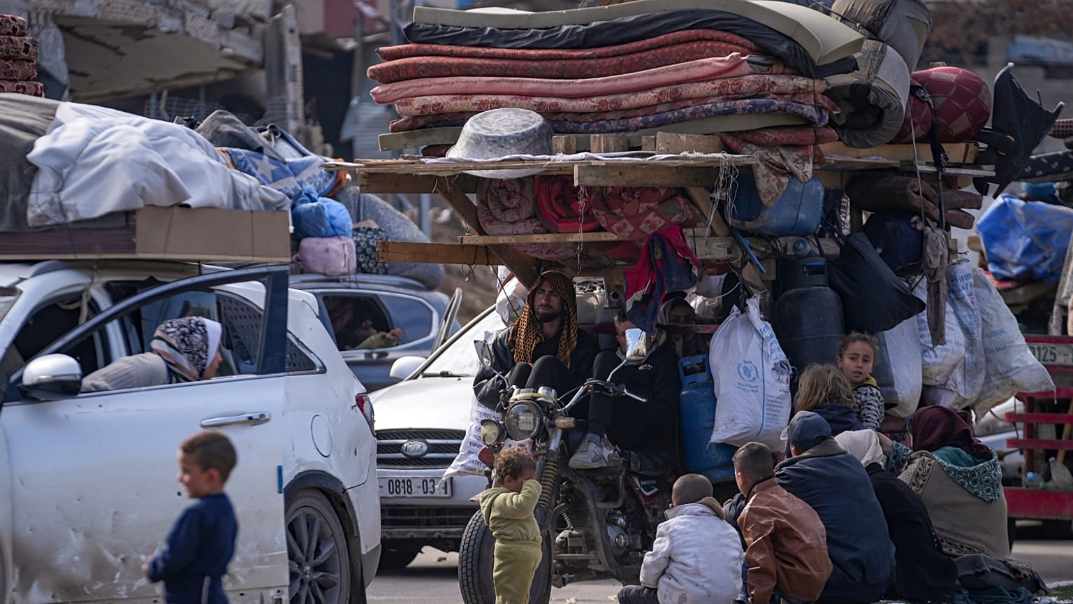 يتجمع النازحون الفلسطينيون مع أمتعتهم بالقرب من حاجز طريق في شارع صلاح الدين، في انتظار العودة إلى منازلهم في الجزء الشمالي من قطاع غزة، الأحد 26 يناير 2025