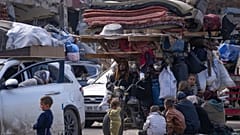 يتجمع النازحون الفلسطينيون مع أمتعتهم بالقرب من حاجز طريق في شارع صلاح الدين، في انتظار العودة إلى منازلهم في الجزء الشمالي من قطاع غزة، الأحد 26 يناير 2025