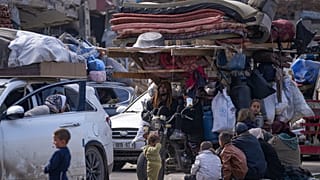 يتجمع النازحون الفلسطينيون مع أمتعتهم بالقرب من حاجز طريق في شارع صلاح الدين، في انتظار العودة إلى منازلهم في الجزء الشمالي من قطاع غزة، الأحد 26 يناير 2025
