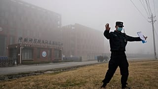 Un addetto alla sicurezza allontana i giornalisti dall'Istituto di virologia di Wuhan dopo l'arrivo di un team dell'Oms per una visita sul campo, 3 febbraio 2021