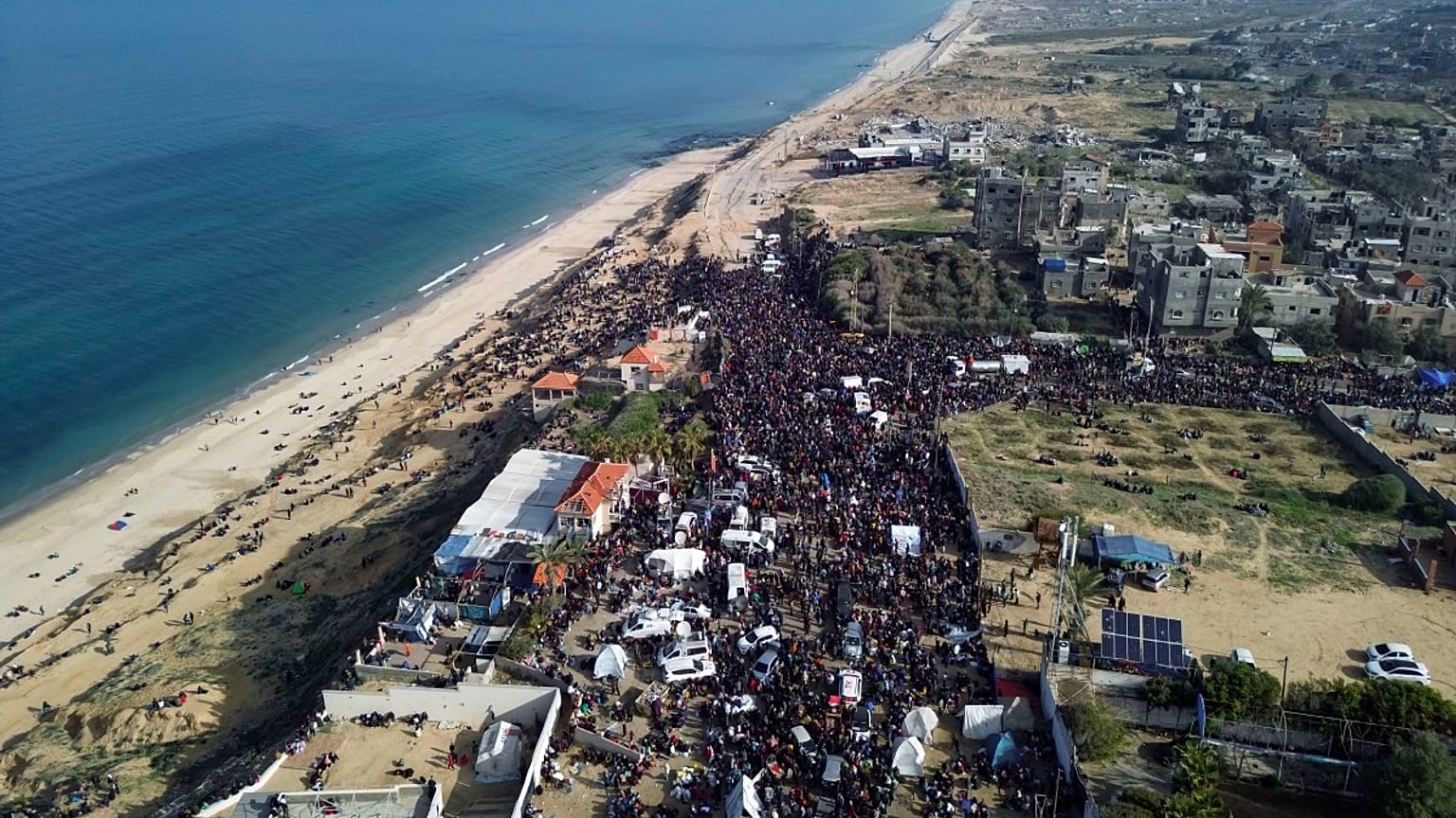 نازحون فلسطينيون يحملون أمتعتهم بالقرب من حاجز في شارع الرشيد، بانتظار العودة إلى منازلهم في شمال قطاع غزة، يوم الأحد 26 يناير/كانون الثاني 2025.