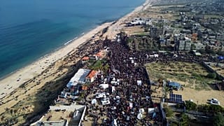 نازحون فلسطينيون يحملون أمتعتهم بالقرب من حاجز في شارع الرشيد، بانتظار العودة إلى منازلهم في شمال قطاع غزة، يوم الأحد 26 يناير/كانون الثاني 2025.