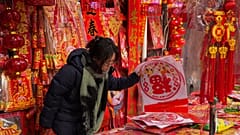 A woman shops for prosperity decorations at a shop in Beijing ahead of the Chinese Lunar New Year 