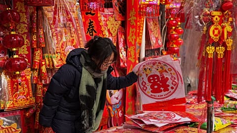 A woman shops for prosperity decorations at a shop in Beijing ahead of the Chinese Lunar New Year 