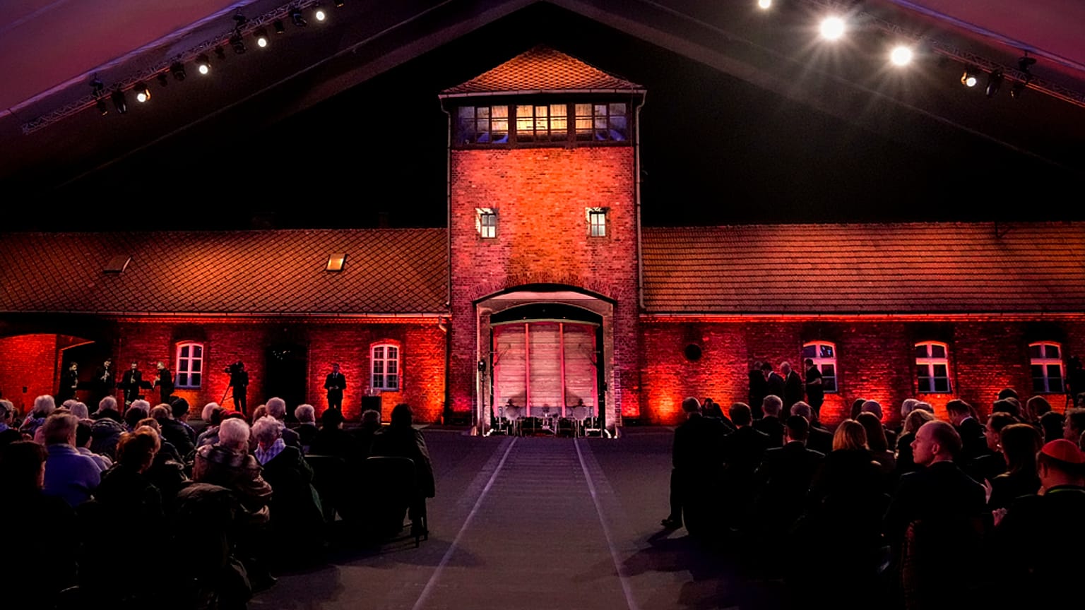 Ocaleni z Holokaustu i goście siedzą w byłym niemieckim nazistowskim obozie koncentracyjnym i zagłady Auschwitz-Birkenau podczas uroczystości upamiętniających 80. rocznicę 