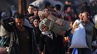 یک زن فلسطینی وسایل خود را برای بازگشت به خانه در شمال نوار غزه حمل می کند، 28 ژانویه 2025
