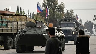 DATEI - Syrische Kämpfer beobachten russische Panzerfahrzeuge, die in der Nähe des syrischen Luftwaffenstützpunkts Hmeimim vorbeifahren, der derzeit von Russland betrieben wird, 16. Dezember 2024.