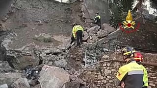 Os bombeiros italianos procuram entre os escombros de um muro que ruiu em Génova, Itália.