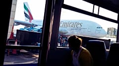 Imagen de una mujer en un autobús del aeropuerto de Dubái, que mira hacia uno de los aviones de la compañía Emirates estacionado en una de las terminales.