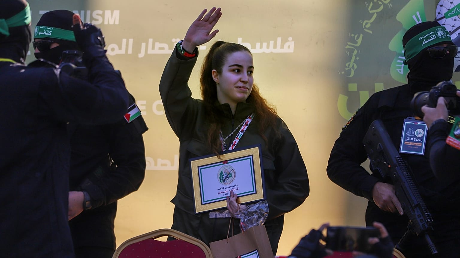 الرهينة الإسرائيلية أغام بيرغر تلوح بيدها أثناء تسليمها إلى الصليب الأحمر من قبل مقاتلين ملثمين من حركة الجهاد الإسلامي في مخيم جباليا للاجئين 