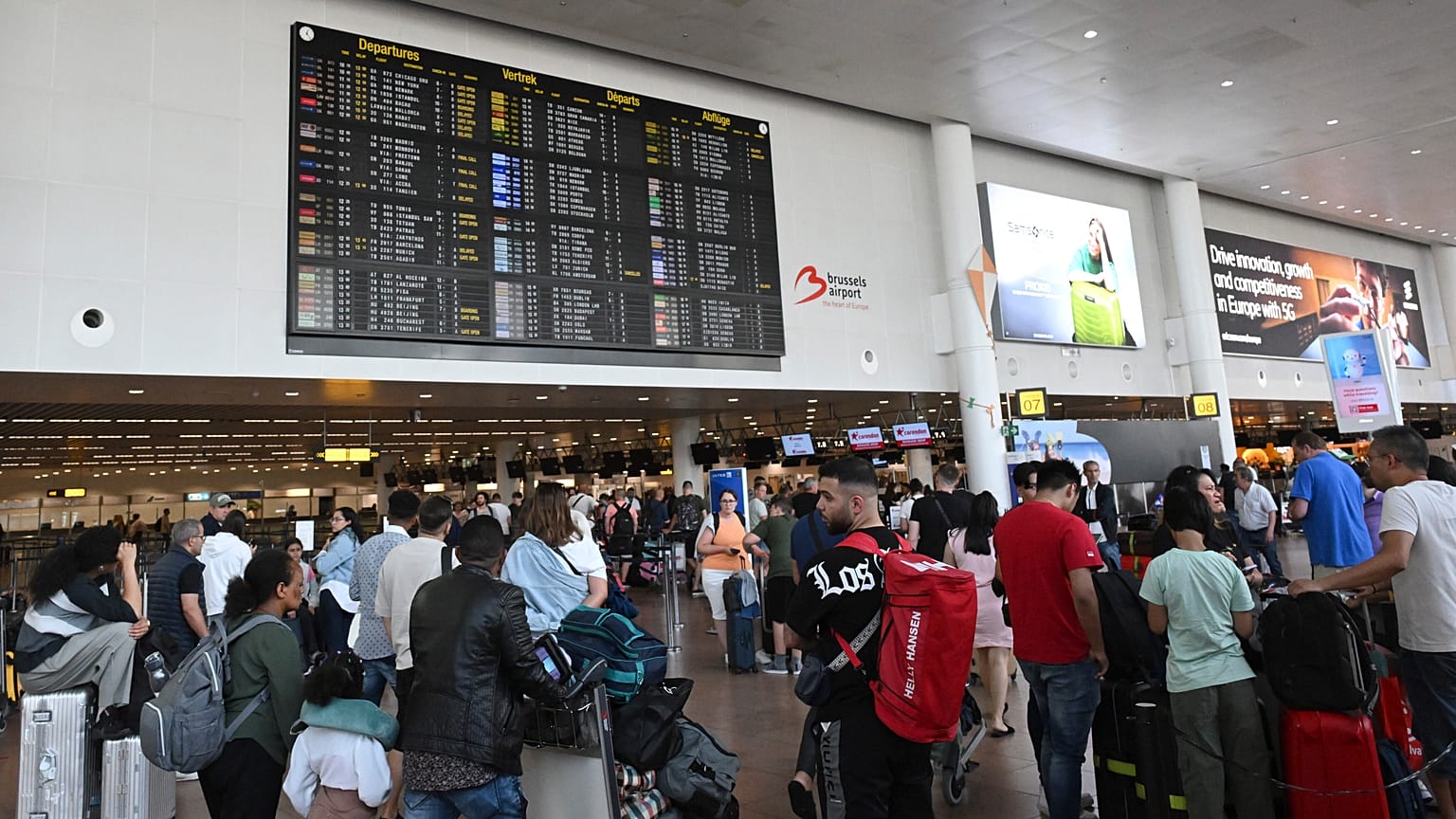 Viajeros esperan información frente a un tablón de salidas en el Aeropuerto Internacional de Bruselas, en Bruselas, 19 de julio de 2024.